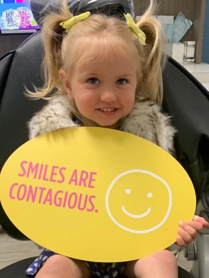 img-patient-forms Happy young girl patient at Edna dentistry. The girl is taking a photo with the doctor holding in hand a card on which is written: "We love our patients".